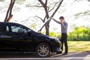 A Man Standing Next to a Broken Down Car Talking on a Phone — Mick’s Towing Service Pty Ltd in Carrara, QLD
