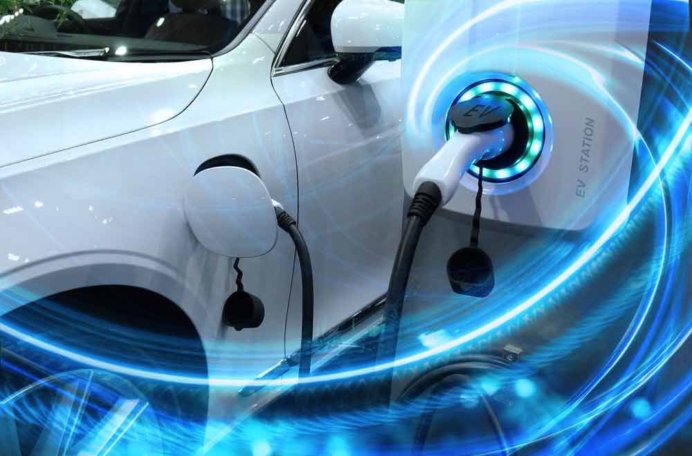 A White Electric Car is Being Charged at a Charging Station — Mick’s Towing Service Pty Ltd in Carrara, QLD