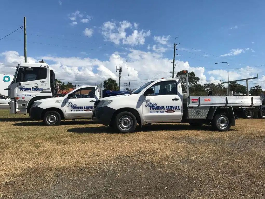 Two Trucks Are Parked Next to Each Other in a Field — Mick's Towing Service Pty Ltd in Carrara, QLD