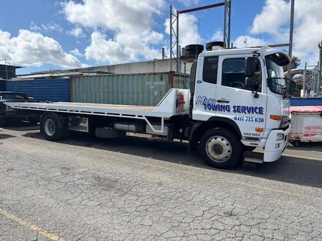 A Truck is Carrying a Large Yellow Bulldozer on a Trailer — Mick's Towing Service Pty Ltd in Carrara, QLD
