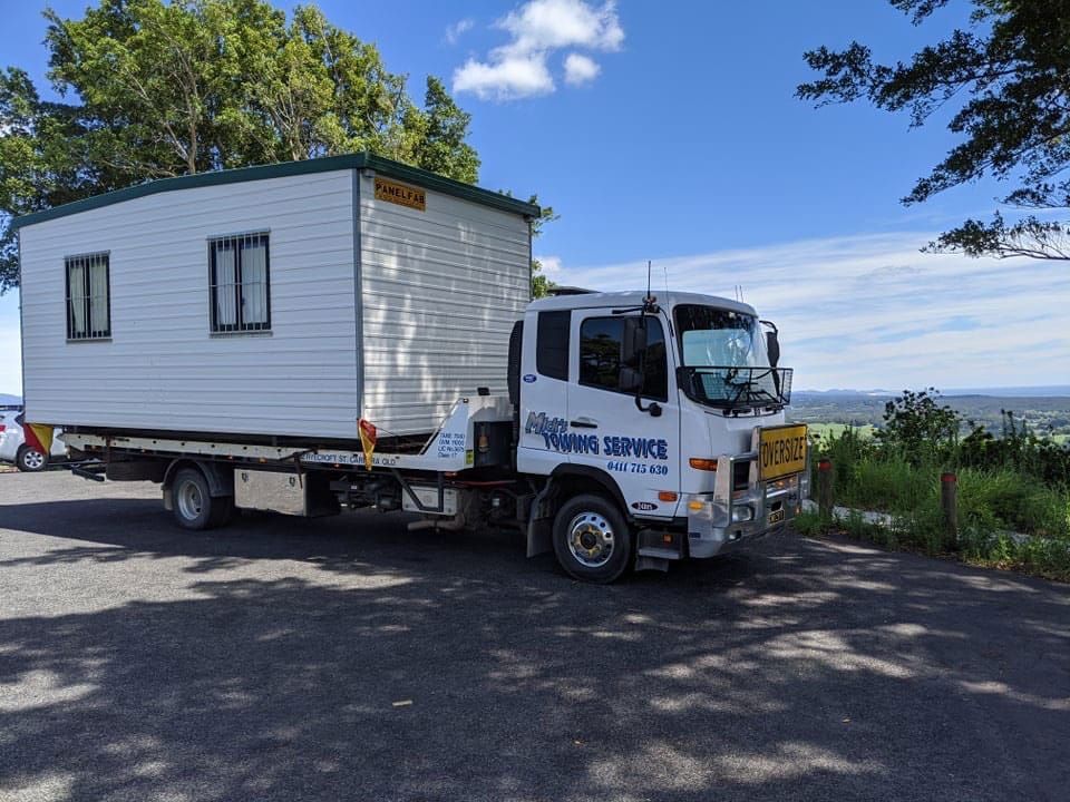 A Tow Truck is Carrying a Small House on the Back of It — Mick’s Towing Service Pty Ltd in Carrara, QLD