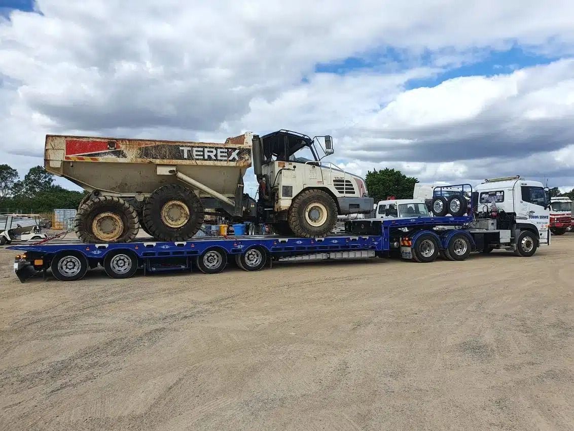 A Terex Dump Truck is Being Transported on a Flatbed Trailer  — Mick's Towing Service Pty Ltd in Carrara, QLD