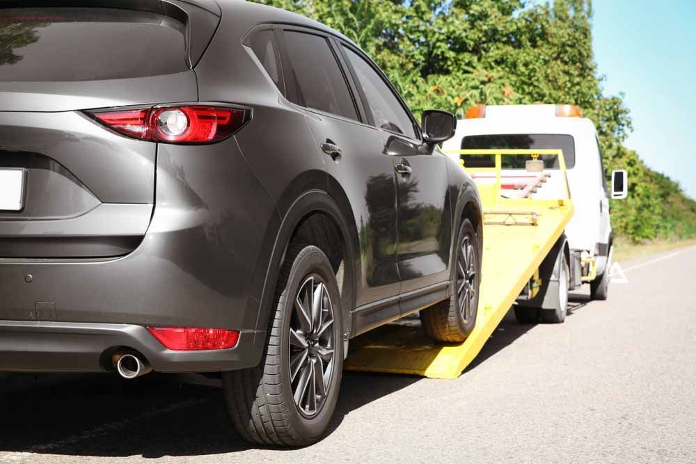 A Car is Being Towed by a Tow Truck on the Side of the Road — Mick's Towing Service in Carrara, QLD