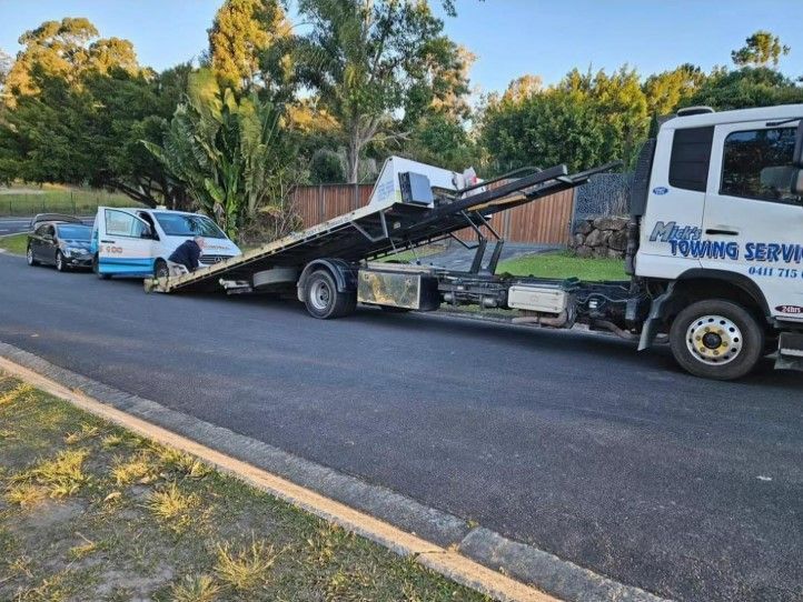 A Tow Truck is Towing a Car on the Side of the Road — Mick’s Towing Service Pty Ltd in Carrara, QLD