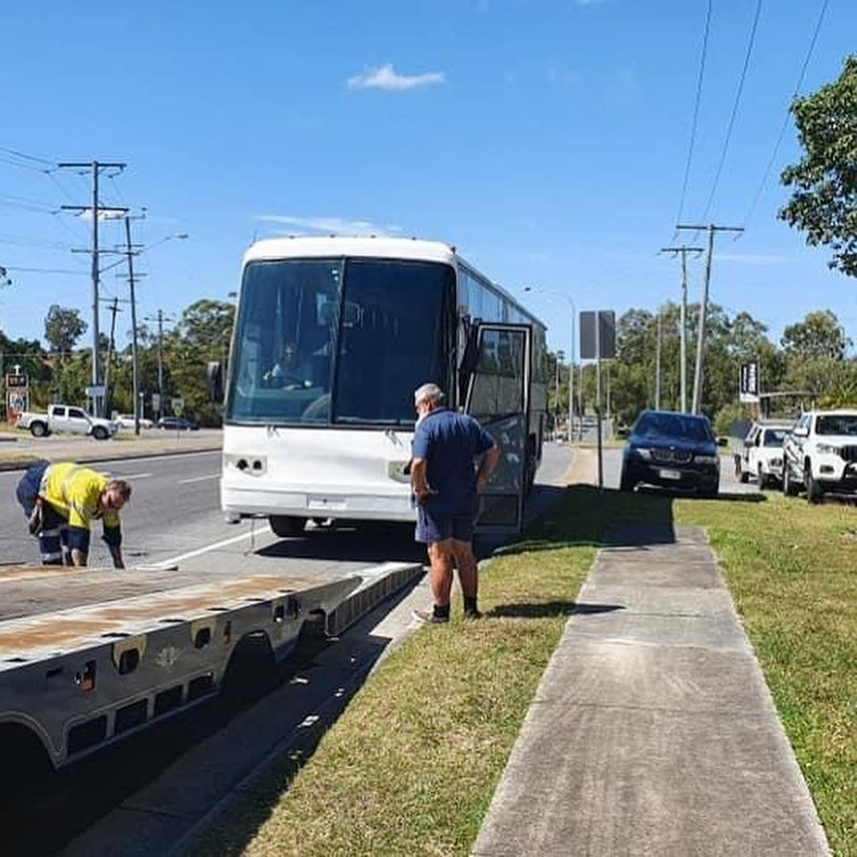 A White Bus is Parked on the Side of the Road — Mick’s Towing Service Pty Ltd in Carrara, QLD