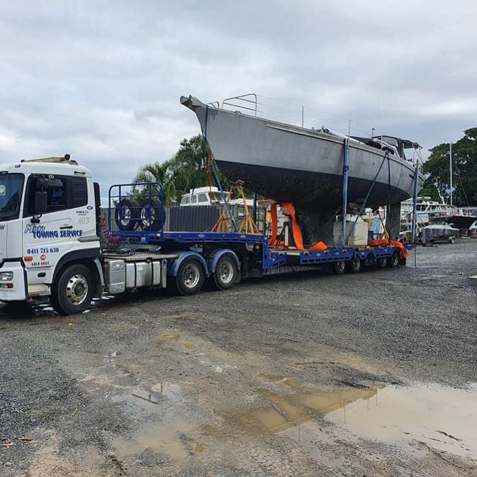 A Large Boat is Being Transported by a Semi Truck — Mick’s Towing Service Pty Ltd in Carrara, QLD