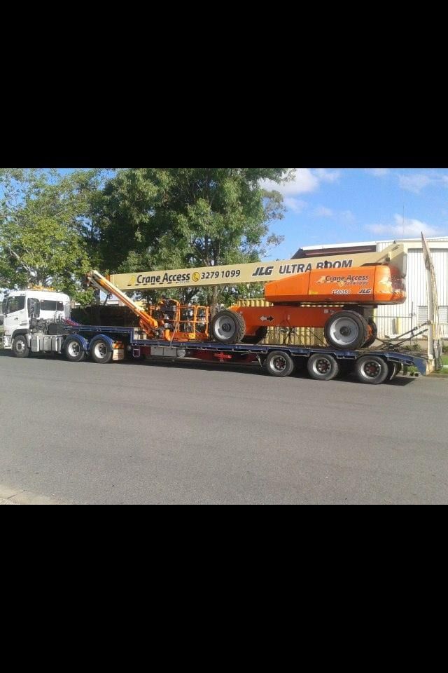 A Large Orange Crane is Being Transported on a Trailer — Mick’s Towing Service Pty Ltd in Carrara, QLD