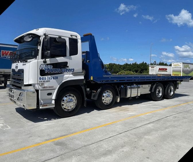A White and Blue Tow Truck is Parked in a Parking Lot — Mick's Towing Service Pty Ltd in Carrara, QLD