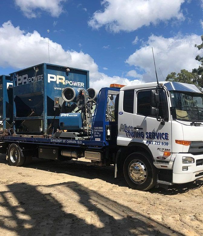 A Tow Truck With a Blue Box on the Back is Parked in the Dirt — Mick's Towing Service Pty Ltd in Carrara, QLD