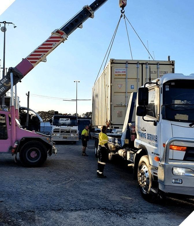 A Crane is Lifting a Shipping Container From the Back of a Tow Truck — Mick's Towing Service Pty Ltd in Carrara, QLD