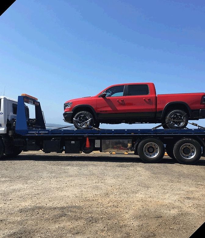 A Red Truck is Sitting on Top of a Flatbed Tow Truck— Mick's Towing Service Pty Ltd in Carrara, QLD