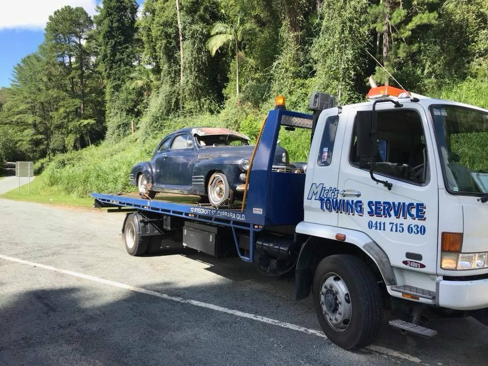 A Towing Service Truck is Carrying a Car on the Back of It — Mick's Towing Service Pty Ltd in Carrara, QLD