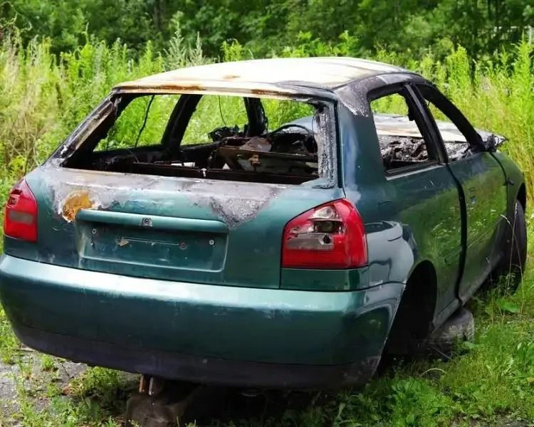 A Green Car With a Broken Windshield is Sitting in the Grass — Mick's Towing Service Pty Ltd in Carrara, QLD