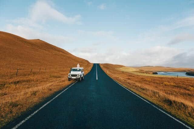 A White Car is Driving Down an Empty Road — Mick’s Towing Service Pty Ltd in Carrara, QLD
