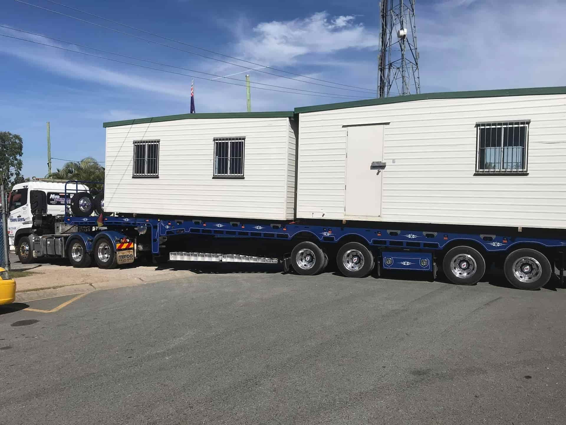 A Truck is Carrying a Trailer With Two Buildings on It — Mick's Towing Service Pty Ltd in Carrara, QLD