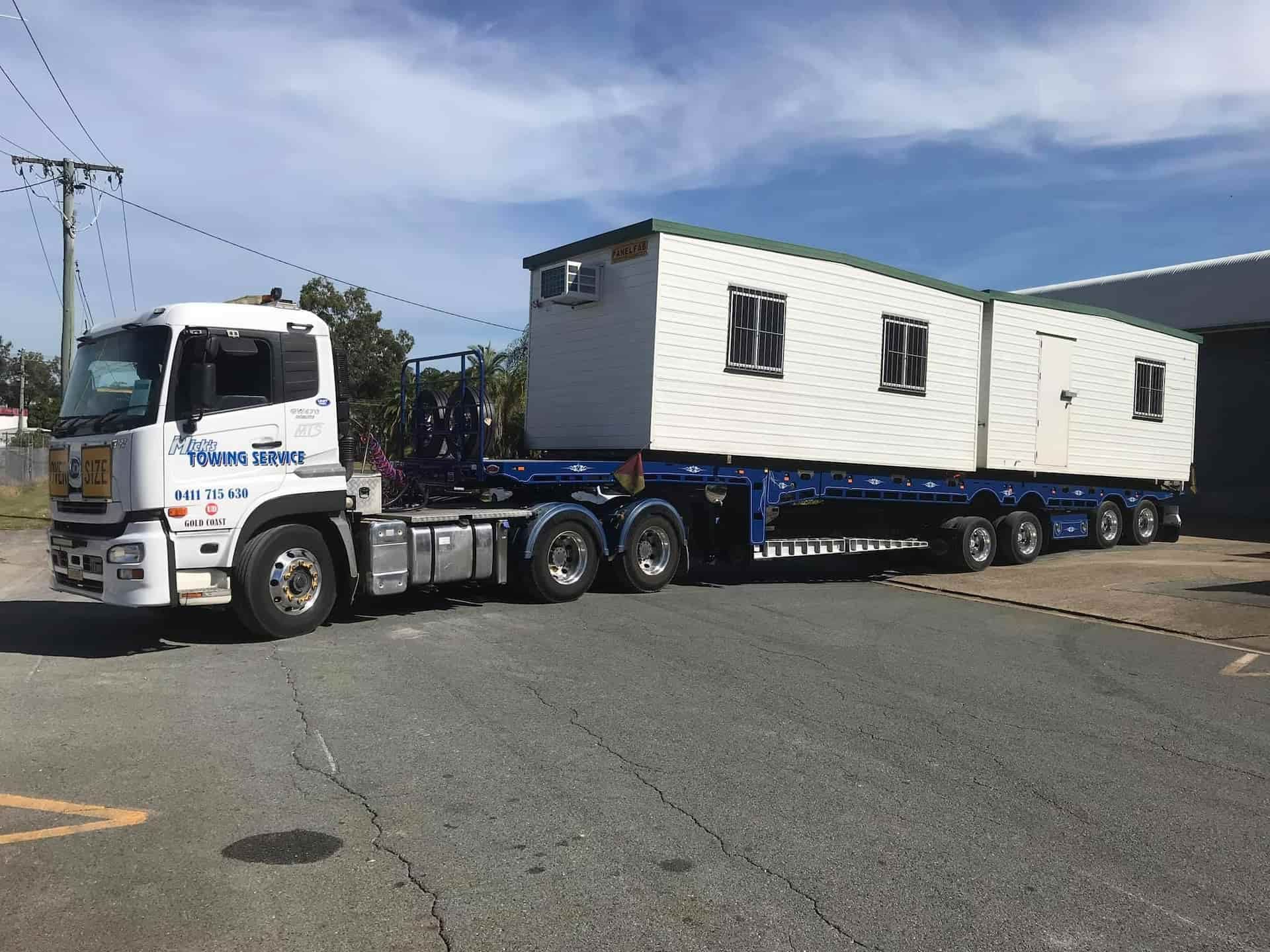 A Truck is Carrying a Trailer With a Container on It — Mick's Towing Service Pty Ltd in Carrara, QLD