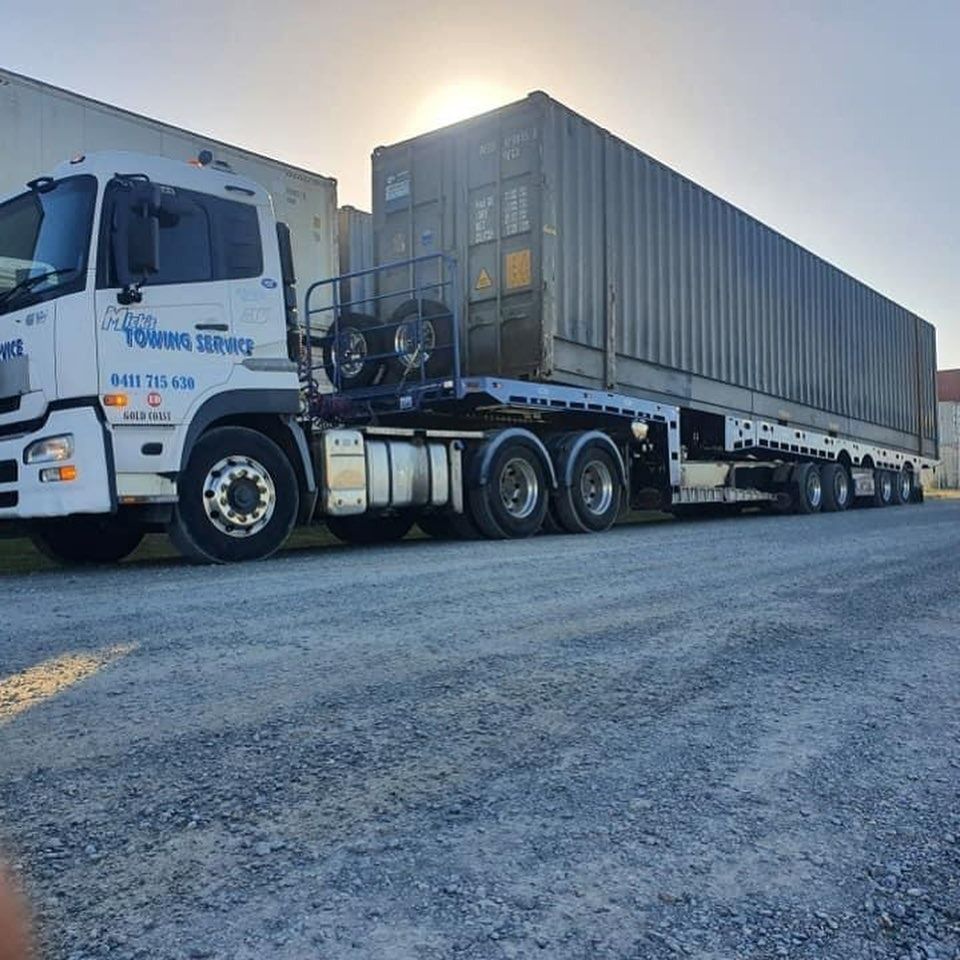 A Semi Truck is Parked on the Side of the Road Next to a Container — Mick's Towing Service Pty Ltd in Carrara, QLD