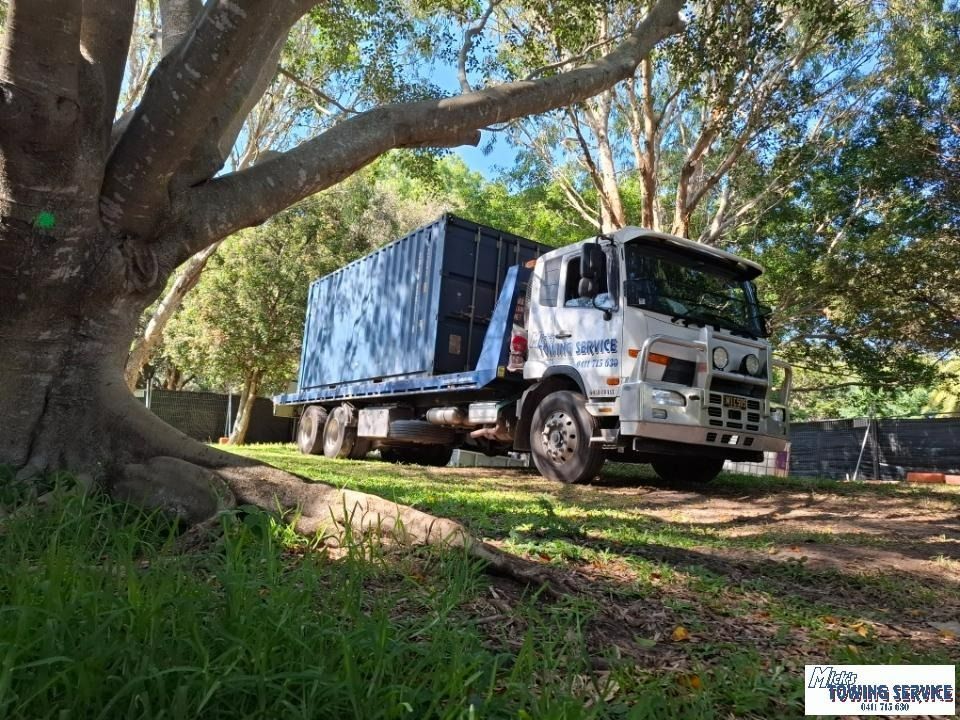 A Truck is Parked in a Grassy Area Next to a Tree — Mick's Towing Service Pty Ltd in Carrara, QLD