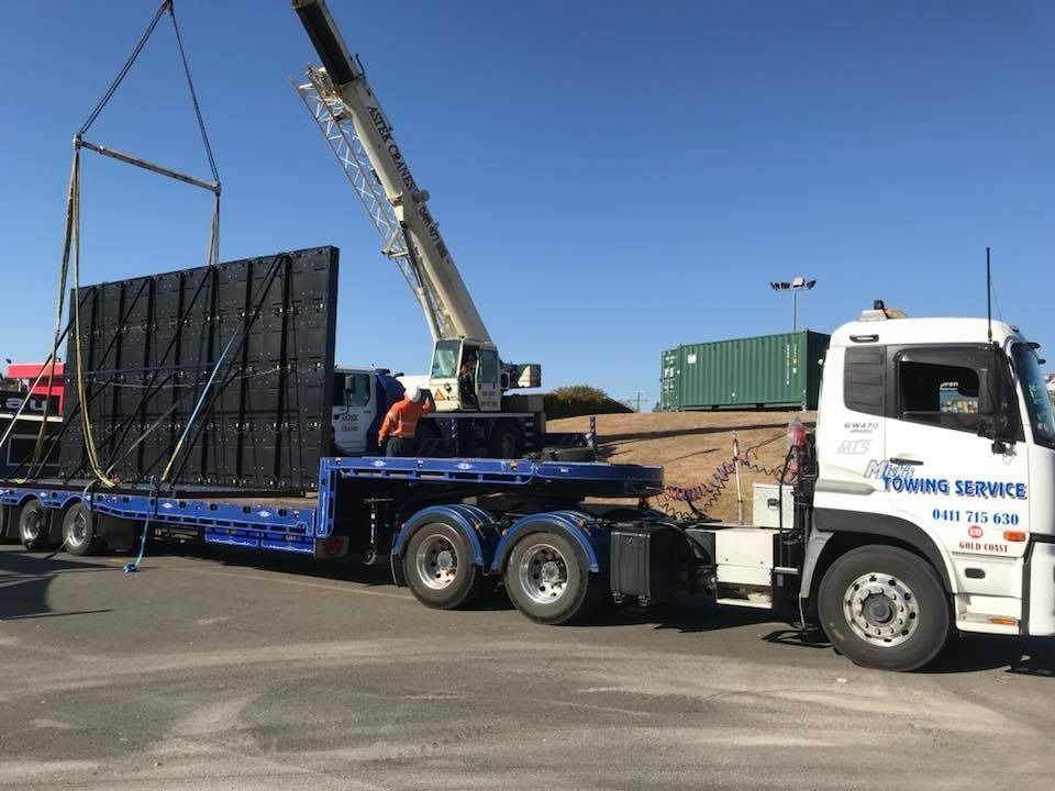 A Truck is Being Towed by a Crane in a Parking Lot — Mick's Towing Service Pty Ltd in Carrara, QLD
