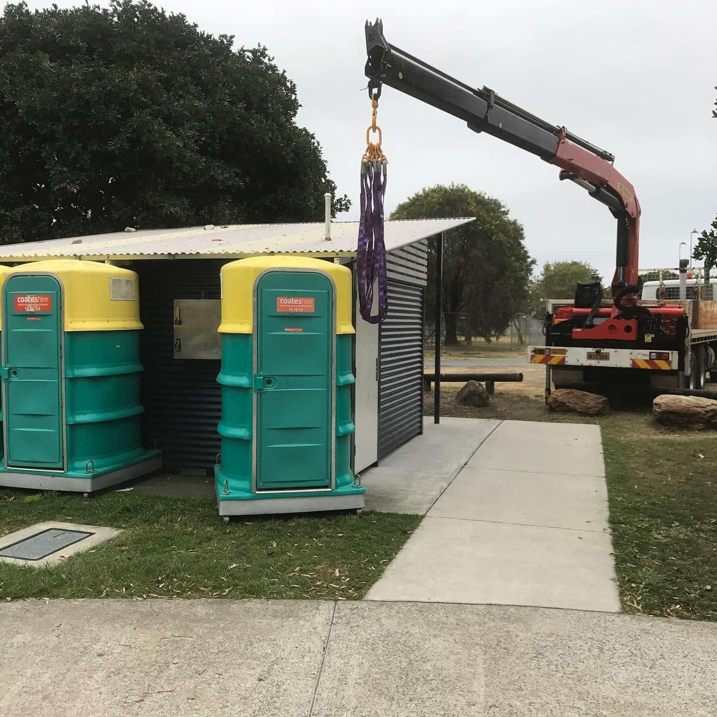 Two Portable Toilets Are Being Lifted by a Crane — Mick's Towing Service Pty Ltd in Carrara, QLD