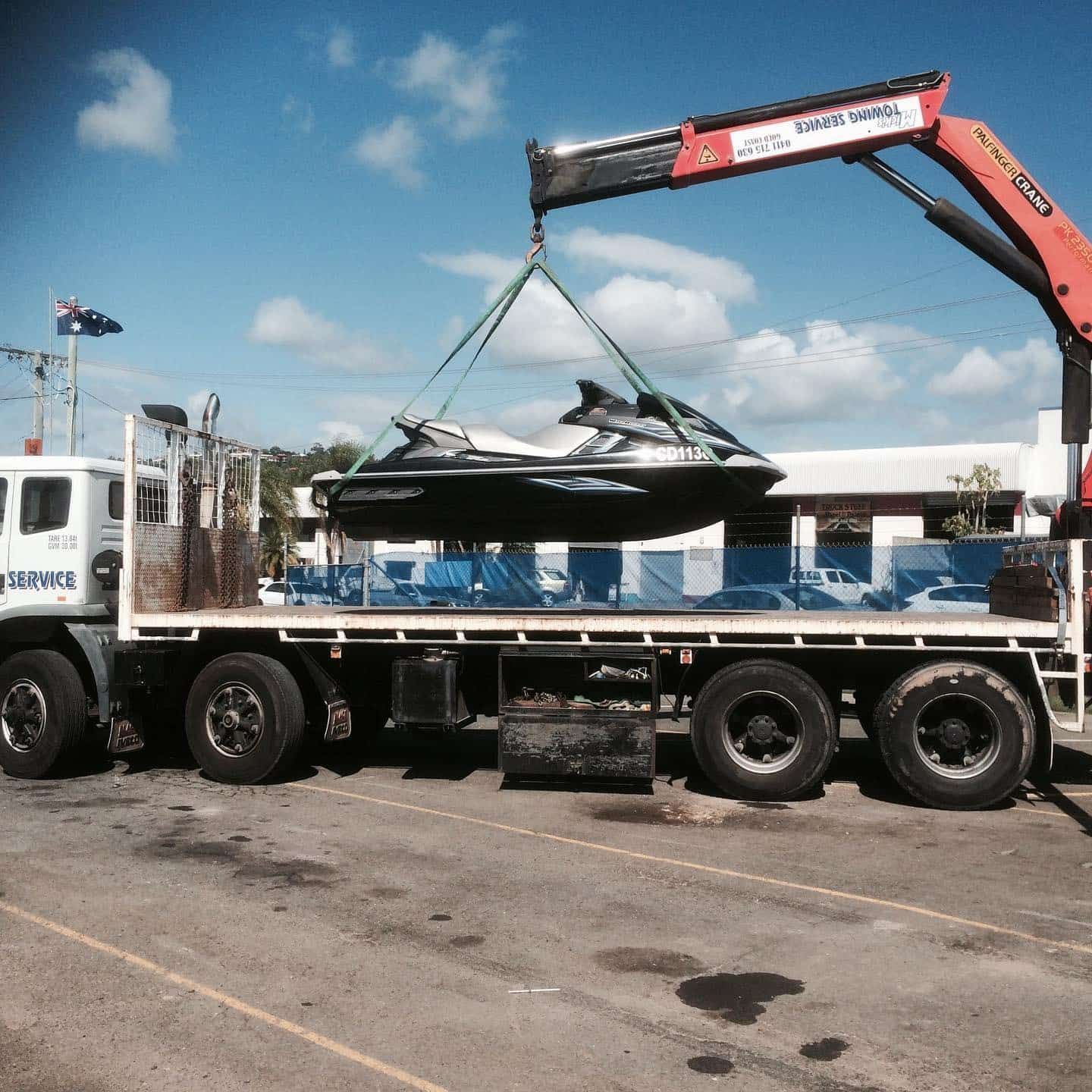A Crane Lifts a Jet Ski From the Back of a Truck — Mick's Towing Service Pty Ltd in Carrara, QLD