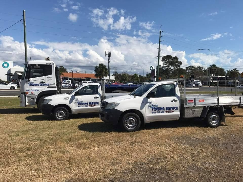Two White Trucks Are Parked Next to Each Other in a Grassy Field — Mick's Towing Service Pty Ltd in Carrara, QLD