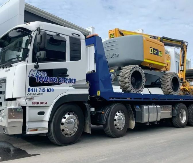 A White Towing Service Truck With a Yellow Excavator on the Back — Mick's Towing Service Pty Ltd in Carrara, QLD