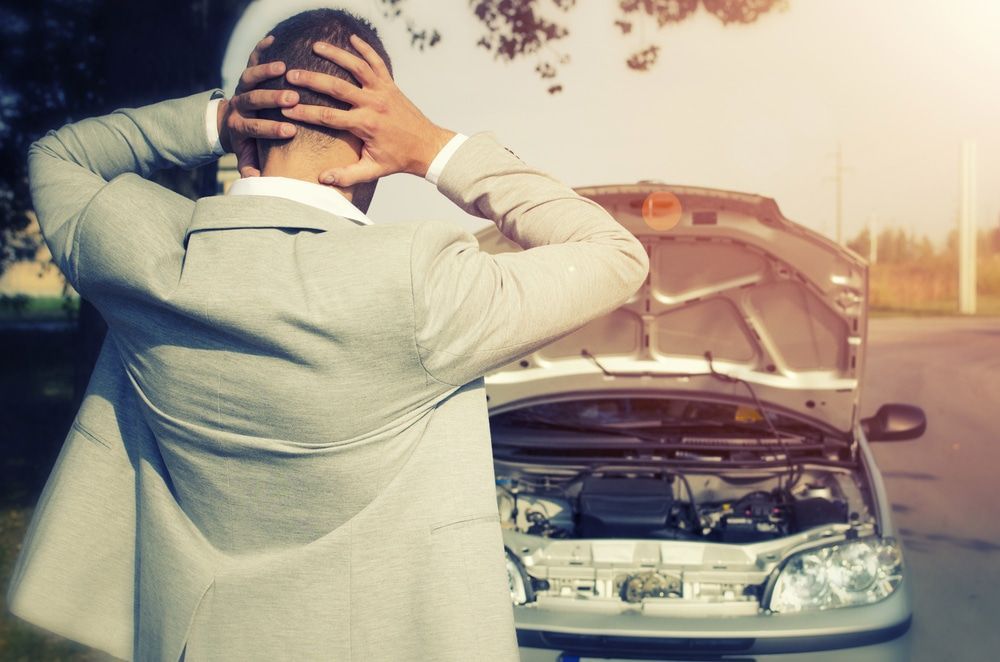 A Man is Standing Next to a Broken Down Car With the Hood Up — Mick’s Towing Service Pty Ltd in Carrara, QLD