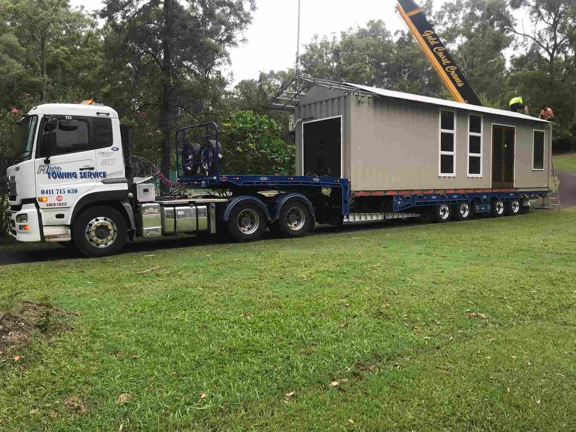 A Semi Truck is Carrying a House on a Trailer — Mick's Towing Service Pty Ltd in Carrara, QLD