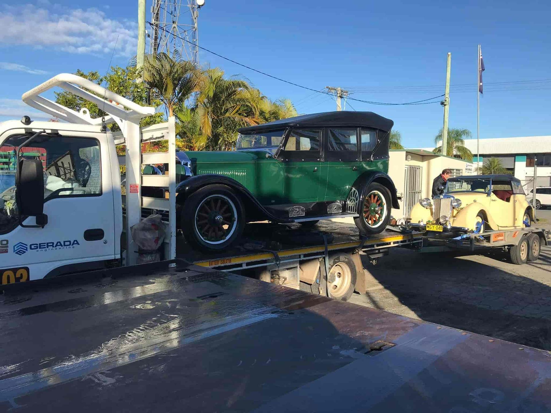 An Old Green Car is Being Towed by a Tow Truck — Mick's Towing Service Pty Ltd in Carrara, QLD