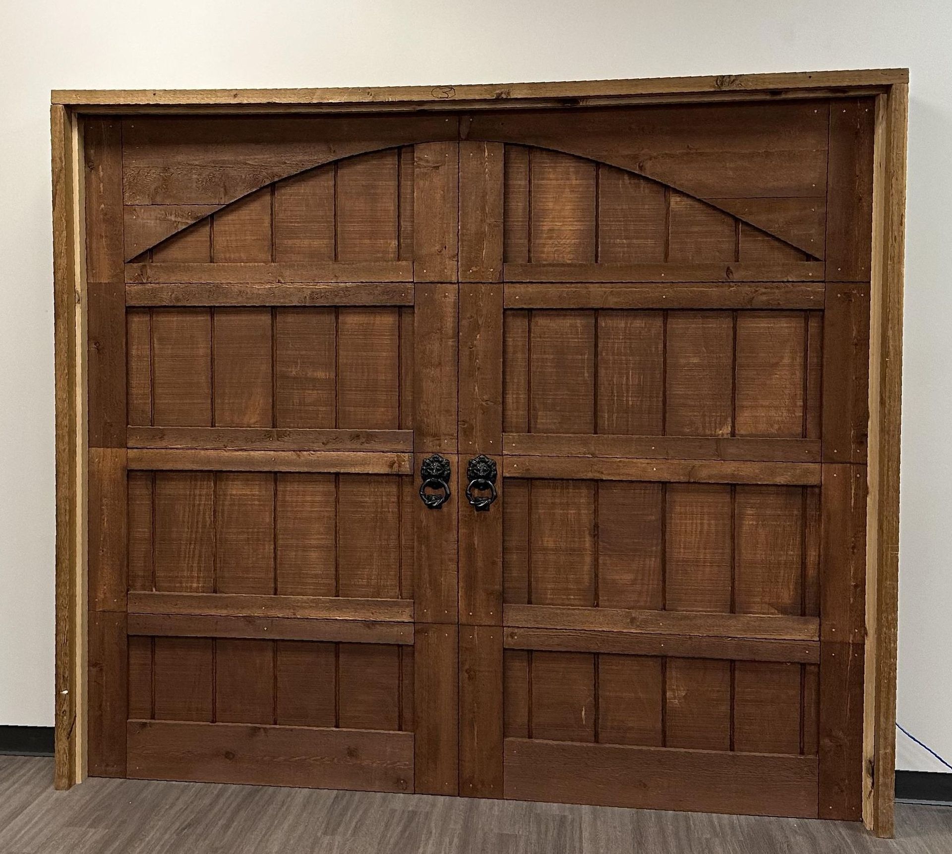 A pair of wooden garage doors are sitting on a wooden floor.