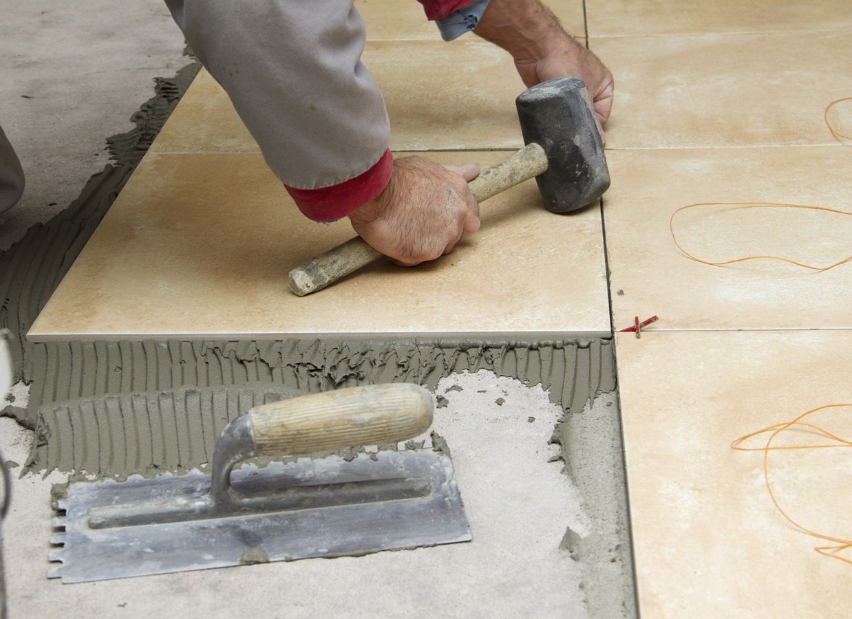 Home improvement, renovation - handyman laying tile with level