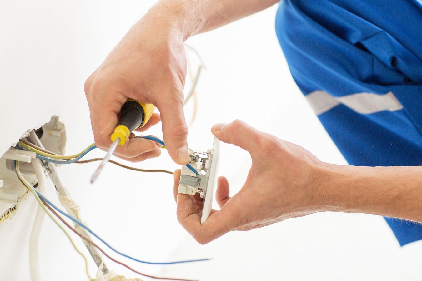 close up of electrician hands with screwdriver fixing socke