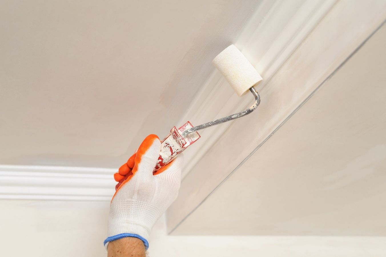 Painter paints the ceiling using a roller