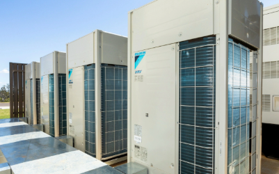 Row of Daikin air conditioning units on a building rooftop, blue sky background.