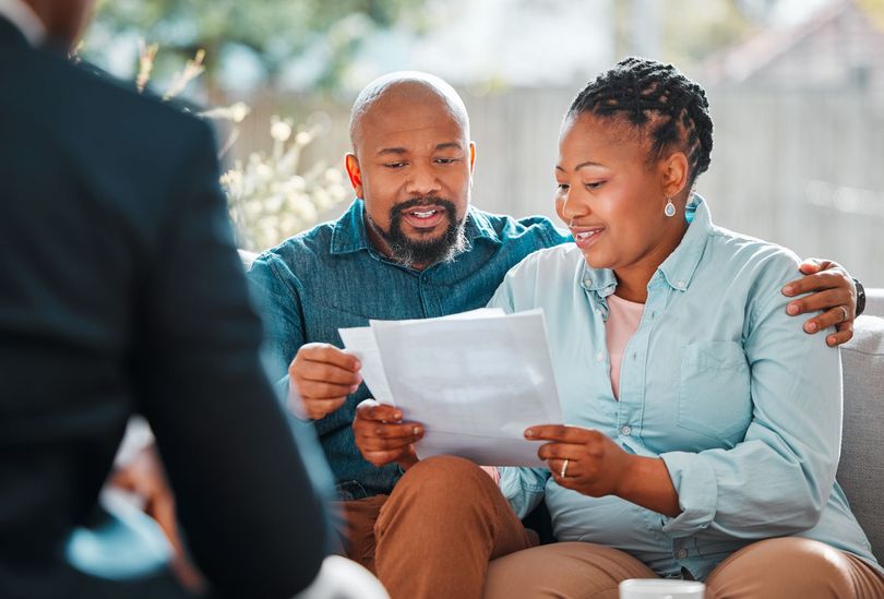 A couple checks a document while consulting with a retirement planning advisor