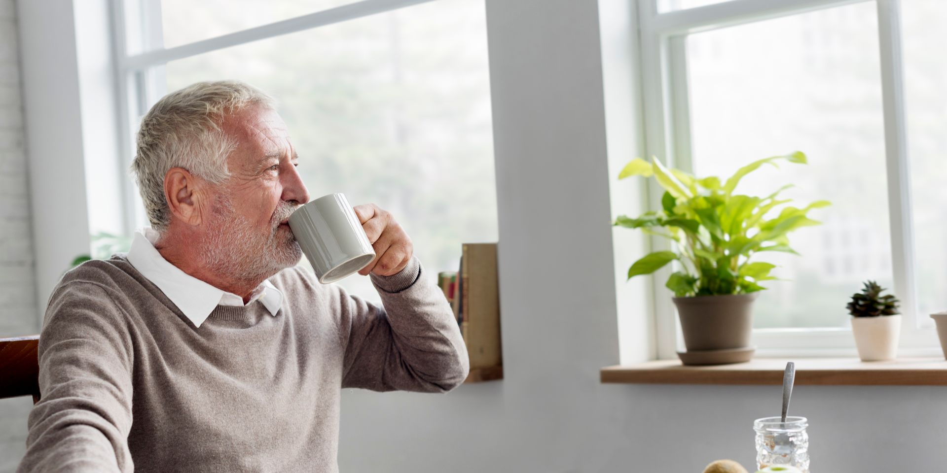Relaxed senior drinking tea cup at home while enjoying peace of mind from smart retirement planning.