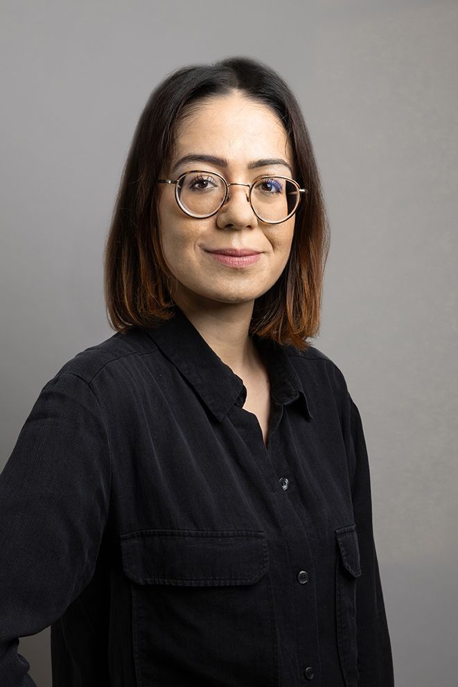 Une femme portant des lunettes et une chemise noire pose pour une photo.