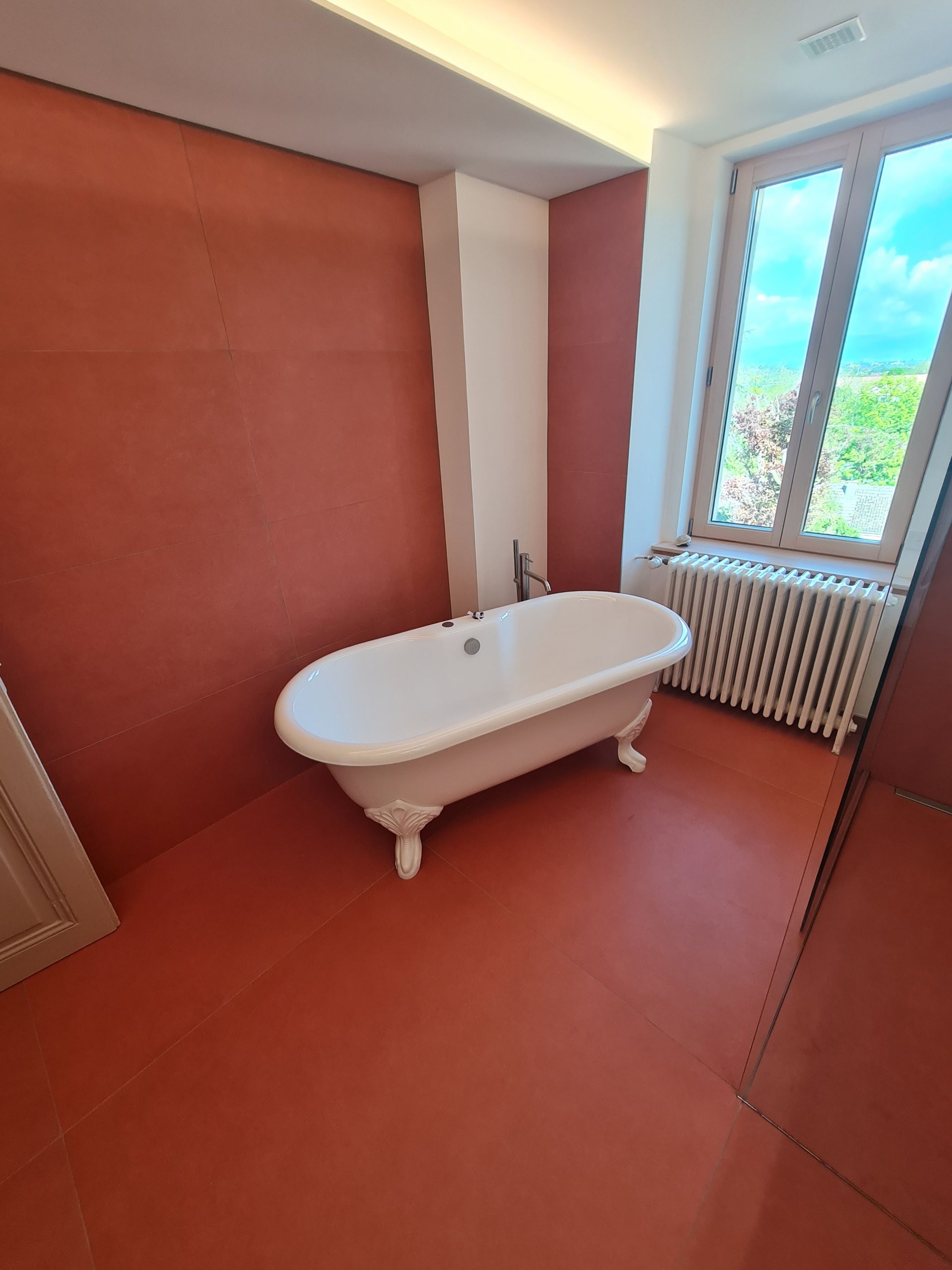 Une baignoire est placée dans une salle de bain à côté d'une fenêtre.