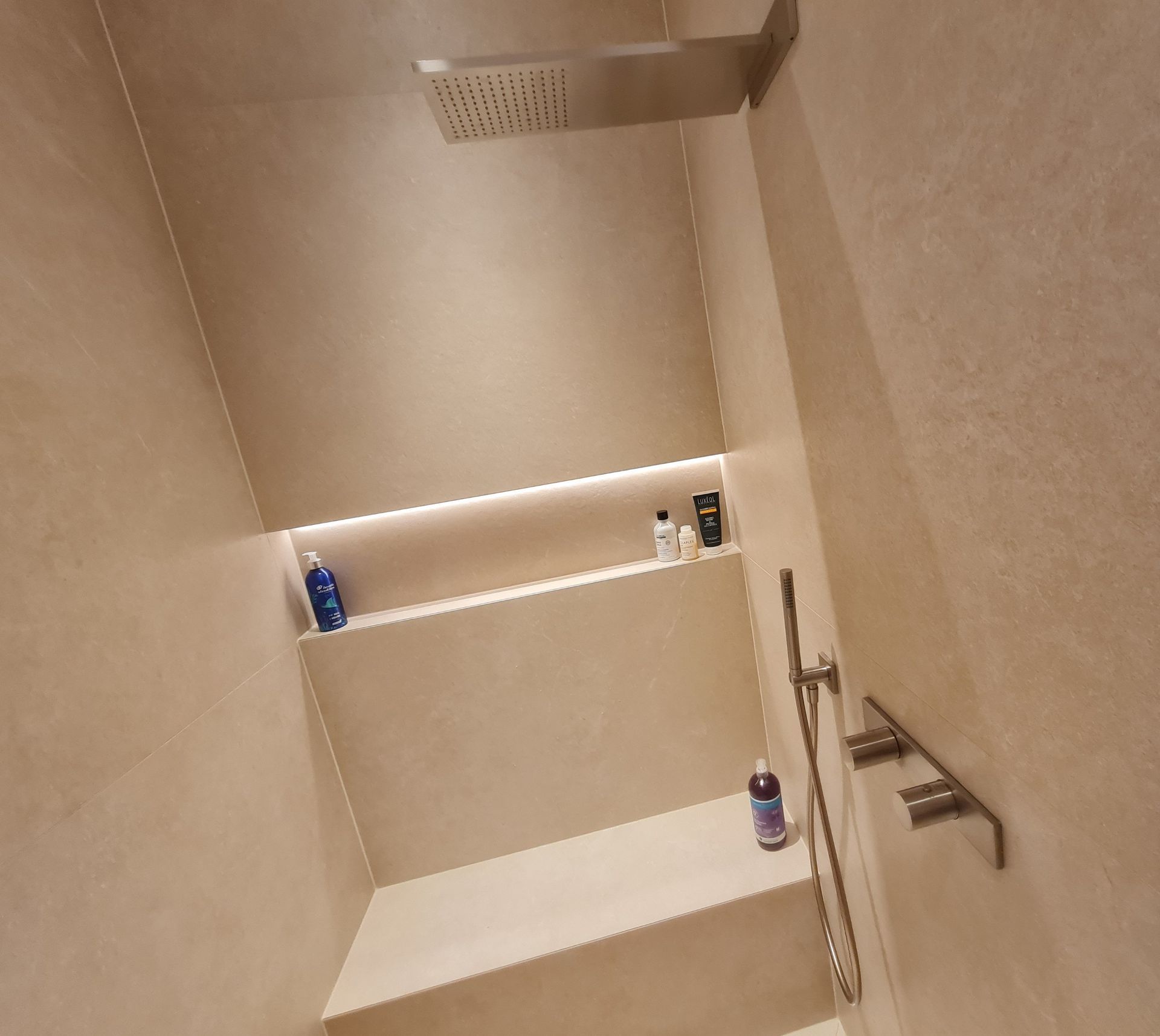 Une salle de bain avec une douche et une étagère avec des bouteilles dessus