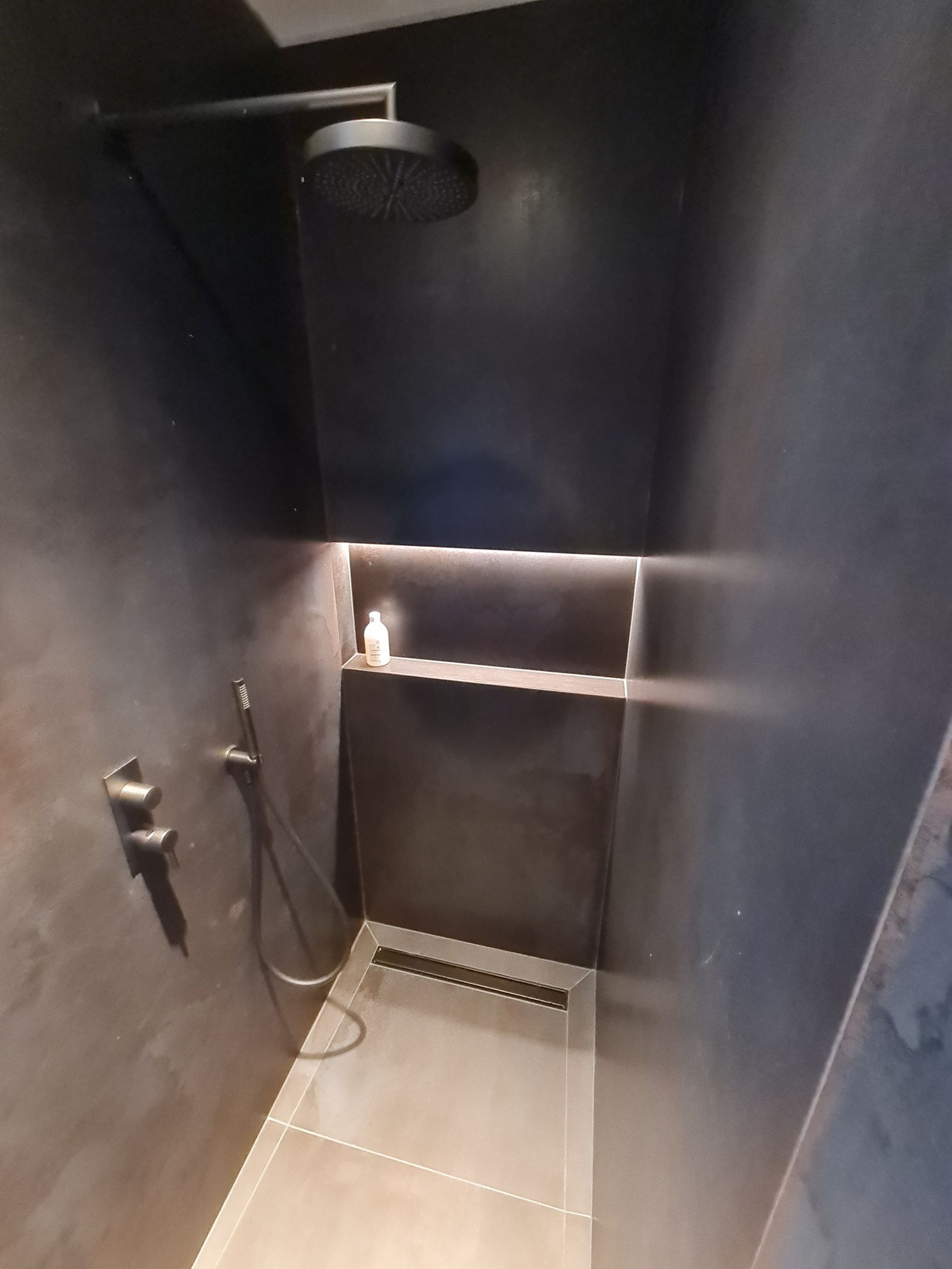 Une douche avec une pomme de douche et un drain dans une salle de bain.