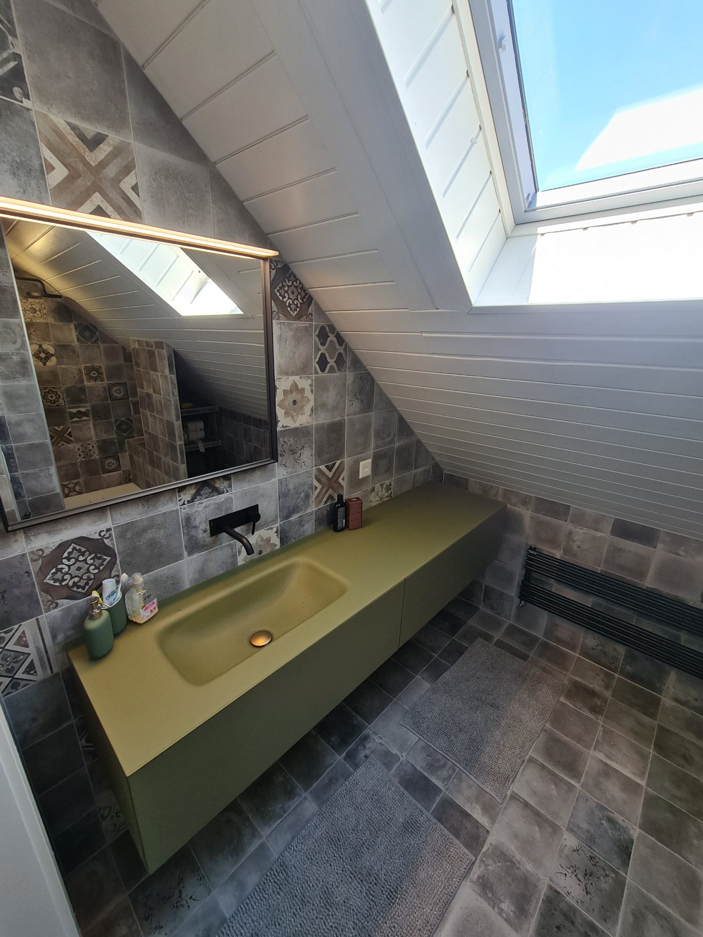 Une salle de bain avec un lavabo, un miroir et une lucarne.