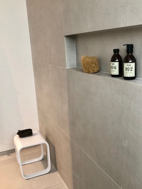 Deux bouteilles de savon et une éponge sont sur une étagère dans une salle de bain