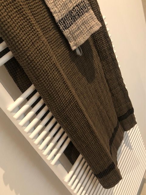 Une serviette marron est suspendue sur un porte-serviettes blanc