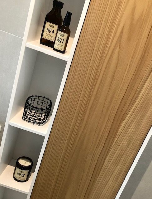 Une étagère de salle de bain avec des bouteilles et des bougies dessus.