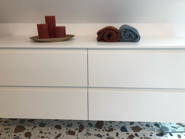 Une commode blanche avec des bougies et des serviettes dessus