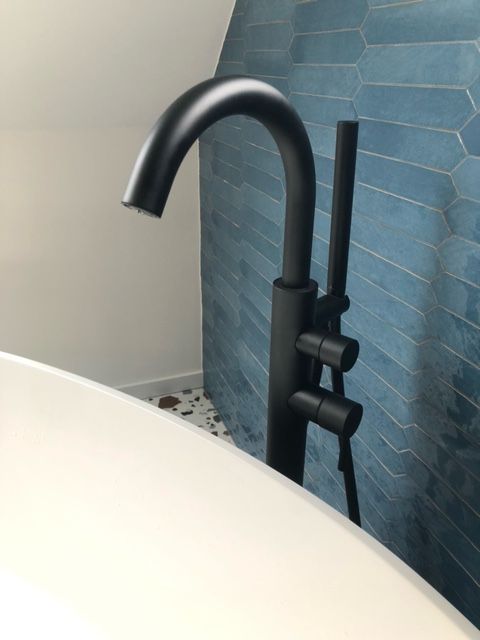 Un robinet de baignoire noir avec un mur bleu en arrière-plan