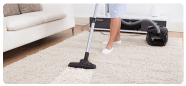 A cleaner washing a carpet with a carpet cleaning machine