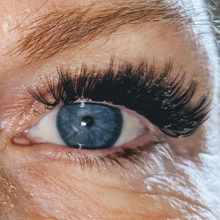 A close up of a woman 's blue eye with long eyelashes.