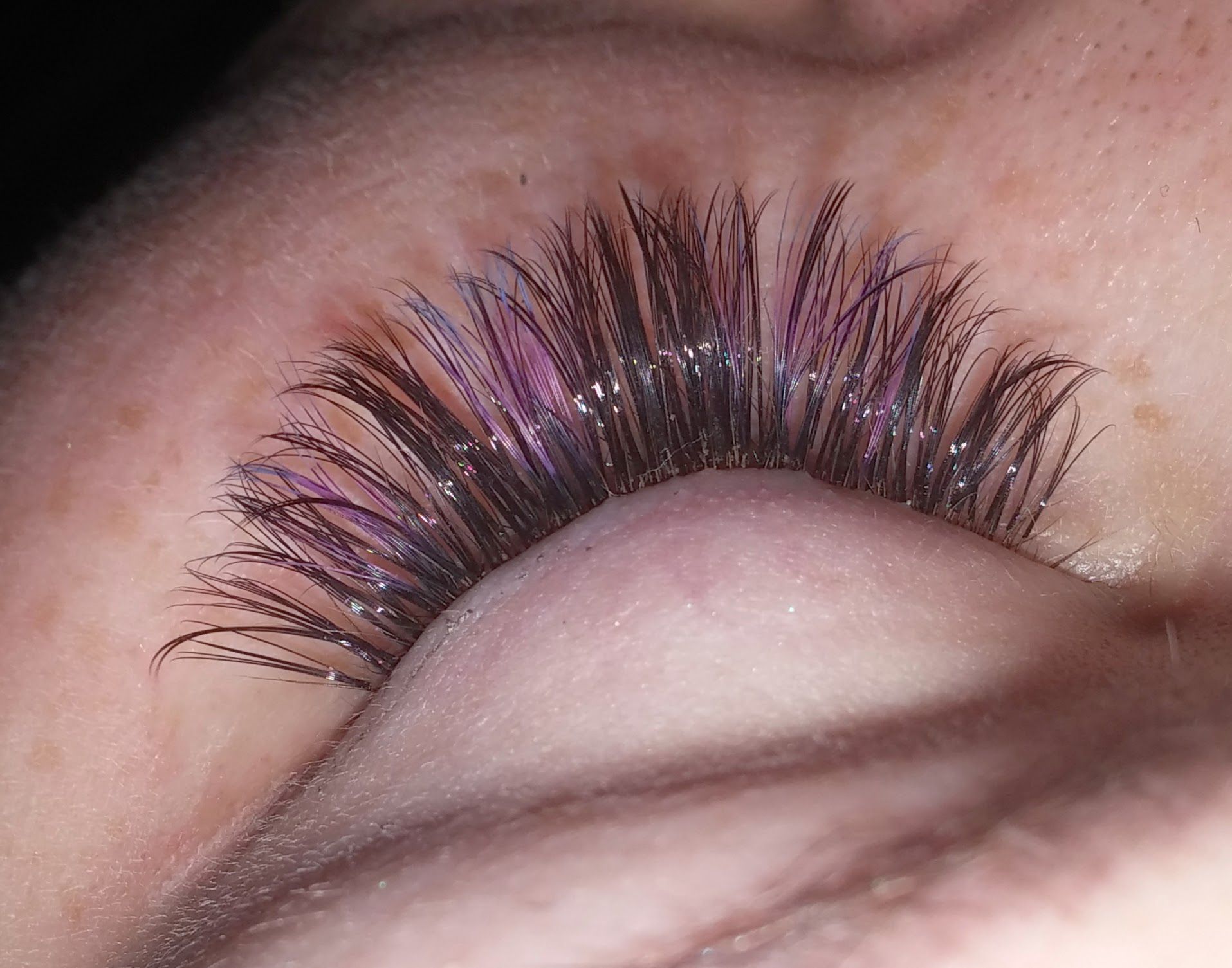 A close up of a woman 's eye with purple eyelashes